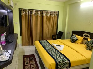 Ein Hotelzimmer mit Bett, Schreibtisch, Stuhl und einem Vorhangfenster.