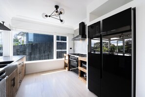 A modern kitchen with a large window, black appliances, and a wooden bench. - Hidden Treasure 3 bedrooms in the Prime Location (Auckland City)