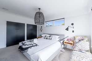 A modern bedroom with a large bed, a wardrobe, a nightstand, and a view of the outdoors. - Hidden Treasure 3 bedrooms in the Prime Location (Auckland City)