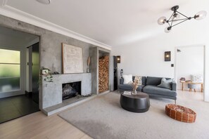 A modern living room with a fireplace, grey sofa, and a round coffee table. - Hidden Treasure 3 bedrooms in the Prime Location (Auckland City)