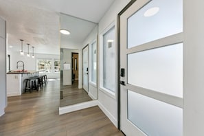 Ein modernes Interieur mit Küchenbereich, Holzboden und einer Glastür zu einem anderen Raum.