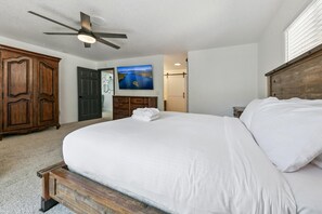 Ein Schlafzimmer mit einem großen Bett, einem Deckenventilator, einem Holzschrank und einem Bild an der Wand.