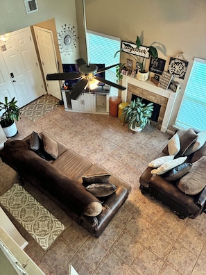 Ein Wohnzimmer mit einem braunen Ledersofa, einem weiteren braunen Sofa und einem Essbereich mit Deckenventilator.