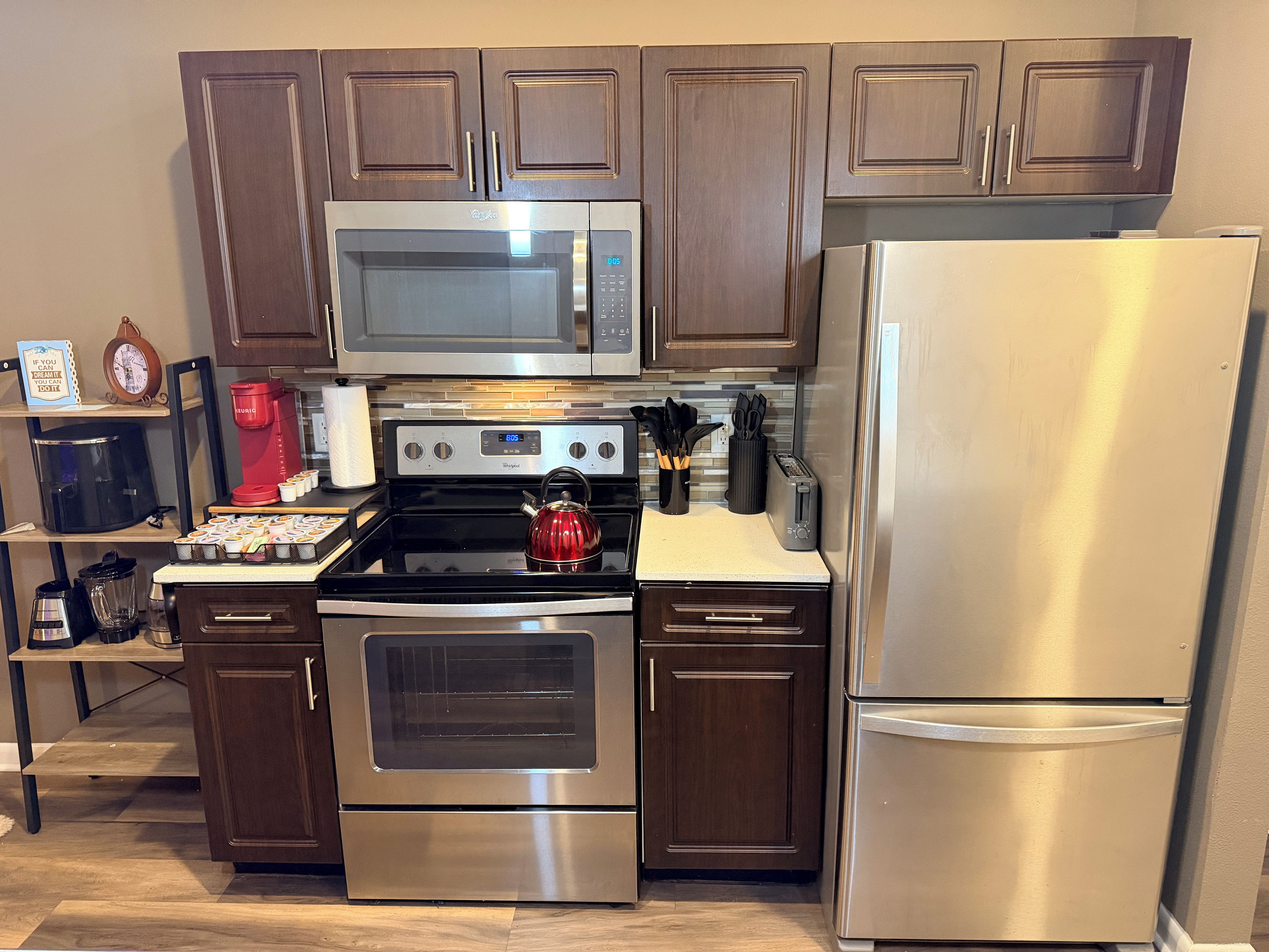 A modern kitchen with stainless steel appliances, wooden cabinets, and a coffee maker.