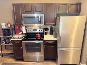 A modern kitchen with stainless steel appliances, wooden cabinets, and a coffee maker.