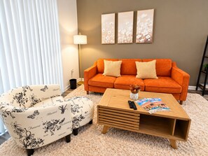 A living room with a sofa, a coffee table, a lamp, and a wall with three framed pictures.