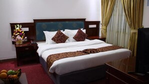 Una camera d'albergo con un letto, un comodino, una TV e una finestra con tende.