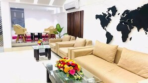 Una moderna hall dell'hotel con un divano, un tavolino da caffè con un bouquet di fiori e una mappa del mondo appesa al muro.