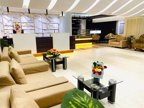 Eine moderne Hotelhalle mit einer Sofaecke, einem Empfangsbereich und einem Essbereich.