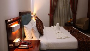 Una camera d'albergo con un letto, un comodino, una lampada e una sedia.
