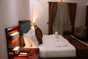 Ein Hotelzimmer mit Bett, Nachttisch, Lampe und einem Sessel.