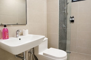 Ein Badezimmer mit weißem Waschbecken, Toilette und einer Duschkabine aus Glas.