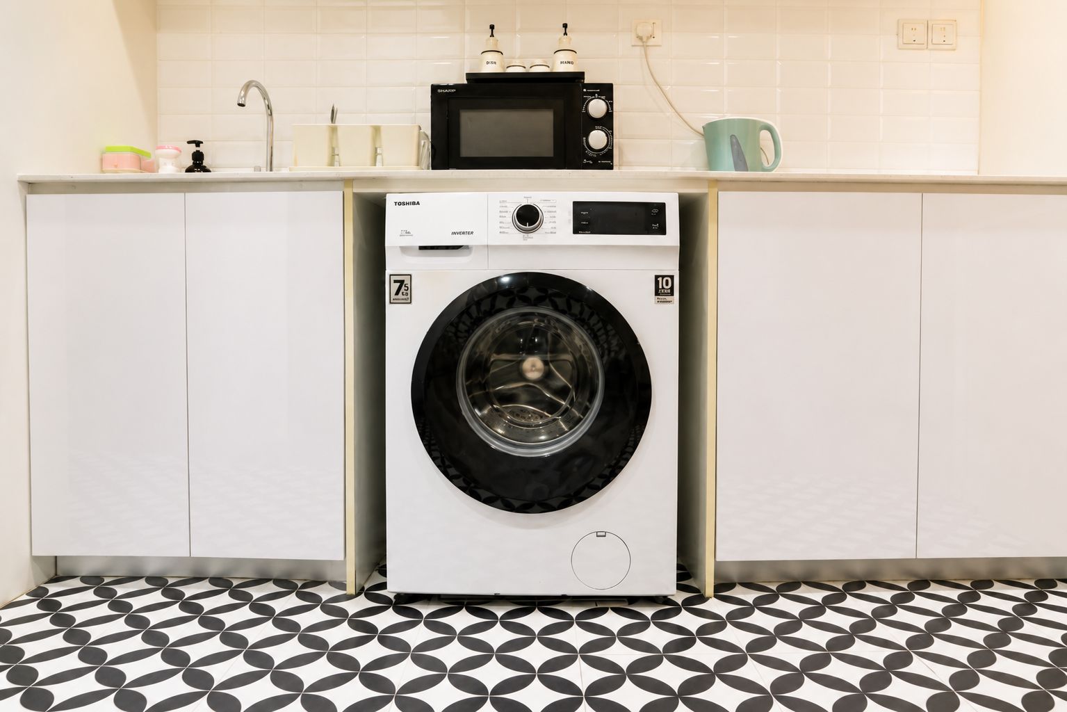 A compact kitchen with a washing machine, a microwave, and a sink.