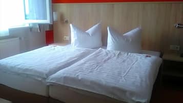 Ein Doppelbett mit weißer Bettwäsche in einem Zimmer mit roten Wänden und einem hölzernen Kopfteil.