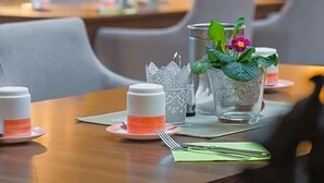 En restaurantscene med borde dækket til spisning, inklusive tallerkener, bestik og glas.