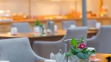 Ein Restaurantambiente mit gedeckten Tischen, darunter Teller, Besteck und Gläser.