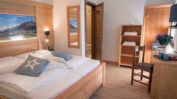 Une chambre à coucher avec un lit en bois, un bureau, une chaise et une vue sur un lac par la fenêtre.