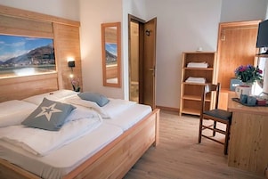 Camera da letto con un letto di legno, una scrivania, una sedia e vista su un lago attraverso una finestra.