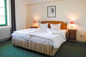 Ein Hotelzimmer mit einem Doppelbett, zwei Nachttischen mit Lampen, einem gerahmten Bild an der Wand und einer Heizung.