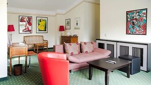 A room with a sofa, a red chair, a table, a lamp, and artwork on the walls. - Brauhaus In Spandau (Berlin)