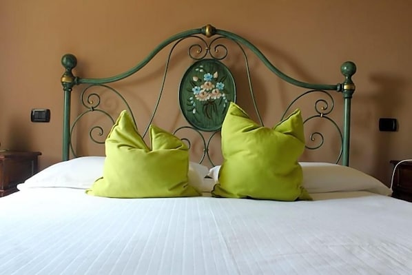 A bed with a metal headboard, two pillows, and a wall-mounted decorative plate. - Masseria Monte Pizzi (Carovilli)