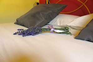 A bed with white bedding, two pillows, a bouquet of lavender, and a small purple bow. - Masseria Monte Pizzi (Carovilli)