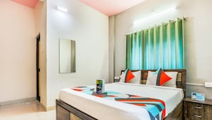 Una habitación de hotel con una cama, una mesita de noche, un espejo y una ventana con cortinas.