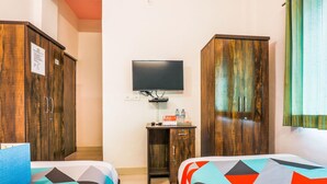 Habitación de hotel con dos camas, televisión, escritorio con silla y armarios de madera.