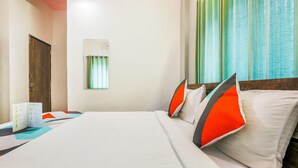Una habitación de hotel con cama, escritorio con silla, ventana con cortinas y puerta.