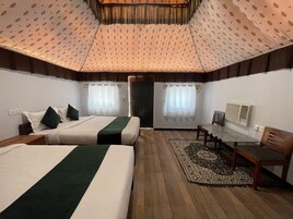 A hotel room with two beds, a small table, a chair, a radiator, and a door.