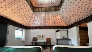 A hotel room with two beds, a desk, chairs, a mirror, and a window. - Unity Holiday Resort (Garudeshwar)