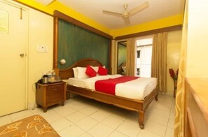 A hotel room with a bed, bedside table, and a ceiling fan. - Hotel Niladri Plaza Siliguri (Siliguri)