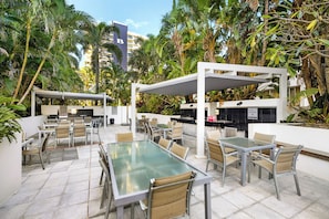 An outdoor patio with tables and chairs, surrounded by lush tropical plants. - The Enderley 2 Bedroom (Surfers Paradise)