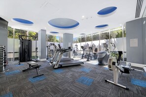 Un gimnasio moderno con máquinas de cardio, equipo de levantamiento de pesas y amplias ventanas.
