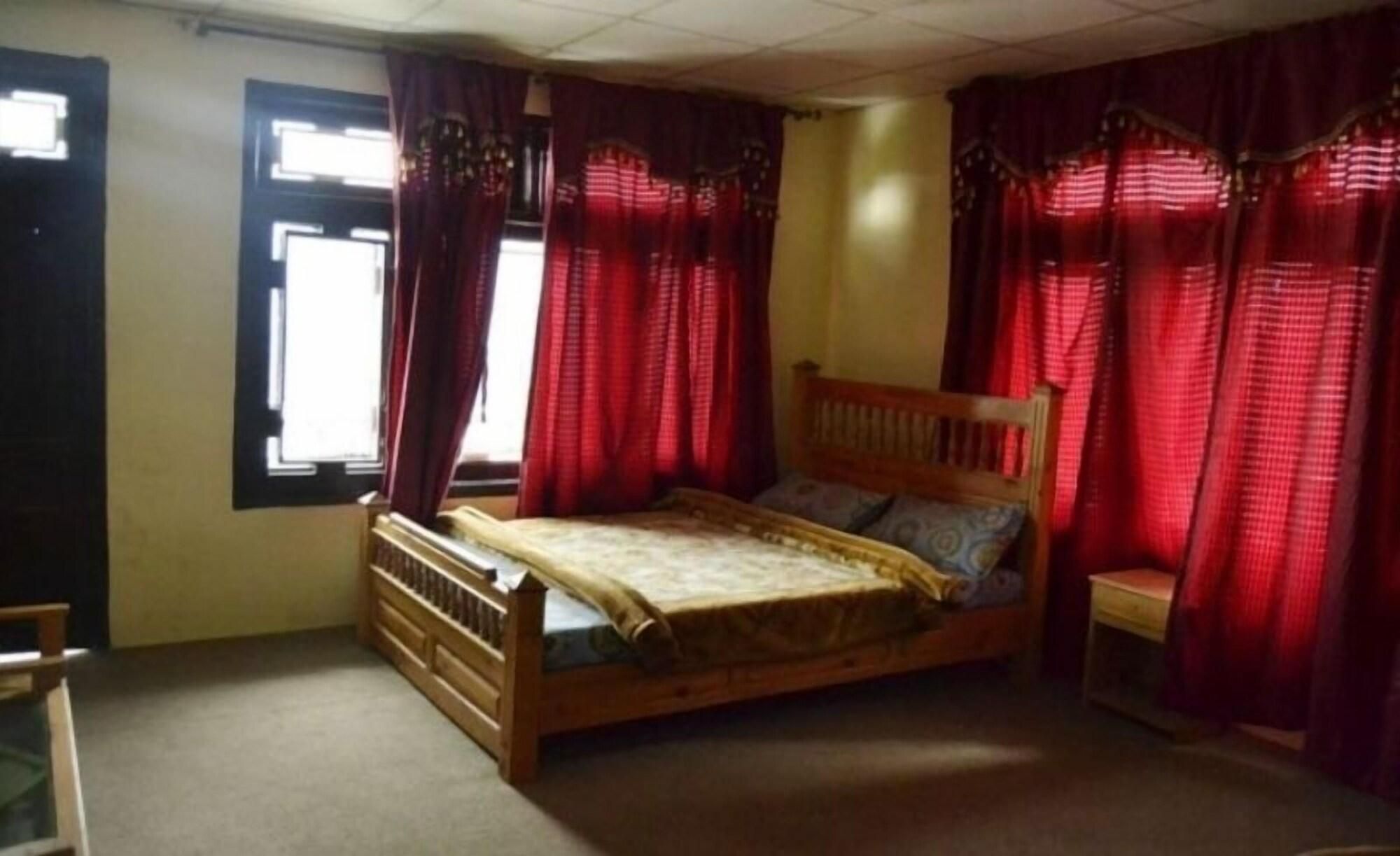 A bedroom with a wooden bed, a nightstand, and red curtains.