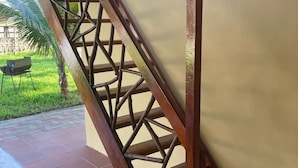 Una escalera de madera con un diseño geométrico que conduce a un espacio cubierto con piso de baldosas.