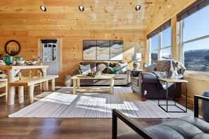 Un intérieur en bois avec un canapé, une table à manger et une grande fenêtre.