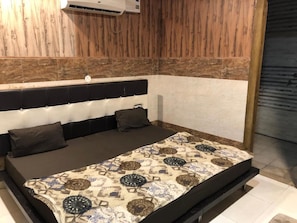 Una habitación con cama, aire acondicionado de pared y paneles de madera.