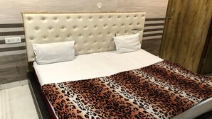 Una cama con cabecera capitonada, ropa de cama blanca y una manta de estampado de leopardo.