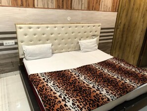 Una cama con cabecera capitonada, ropa de cama blanca y una manta de estampado de leopardo.