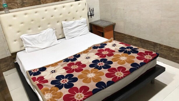 Una cama con cubrecama floral, una mesita de noche de madera y una pared con diseño de paneles de madera.