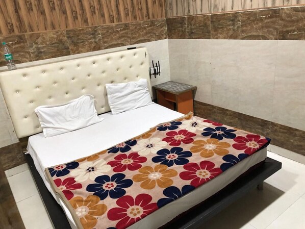 Una cama con cubrecama floral, una mesita de noche de madera y una pared con diseño de paneles de madera.