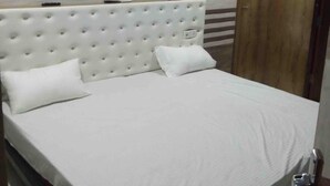 Una cama con cabecera, una puerta de madera y un equipo de aire acondicionado en la pared.