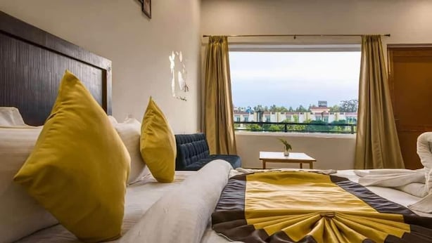 A hotel room with two beds, a small table, and a view of the city.
