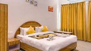 A hotel room with a wooden bed, a bedside table, a nightstand, and a window with yellow curtains.