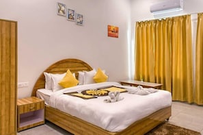 A hotel room with a wooden bed, a bedside table, a nightstand, and a window with yellow curtains. - Pristine Nature View By Group Of Hotels18 (Ramnagar)