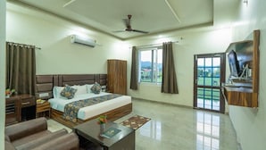 A hotel room with a bed, a desk, a chair, a television, and a window with curtains.