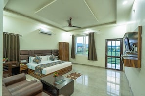 A hotel room with a bed, a desk, a chair, a television, and a window with curtains. - Pristine Nature View By Group Of Hotels18 (Ramnagar)
