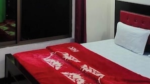 Un dormitorio con una cama, un ventilador de techo, una ventana con cortinas y una pared de acento roja.