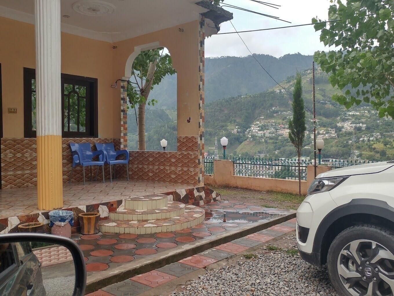 Un espacio de estar al aire libre cubierto con sillas, piso de baldosas y vistas a un paisaje montañoso.